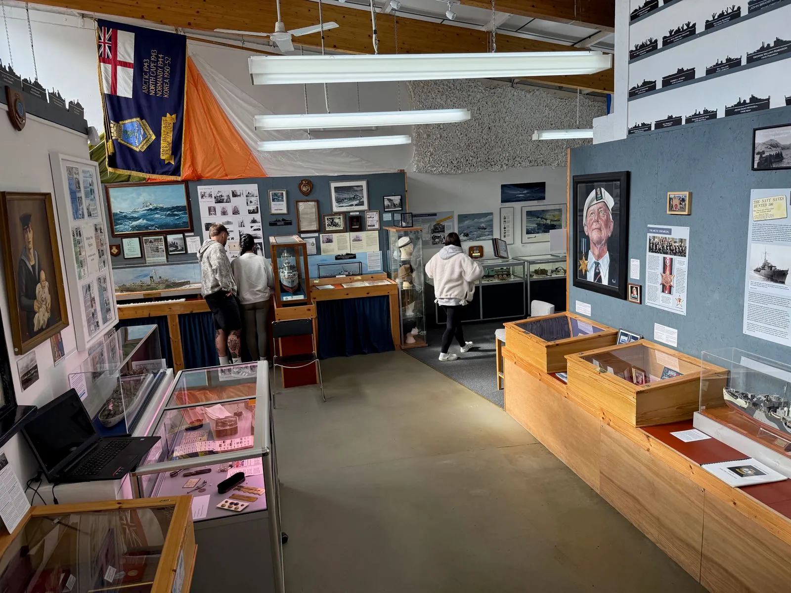 Interiér muzea s námořní tématikou, vystavené exponáty a návštěvníci prozkoumávající expozice.