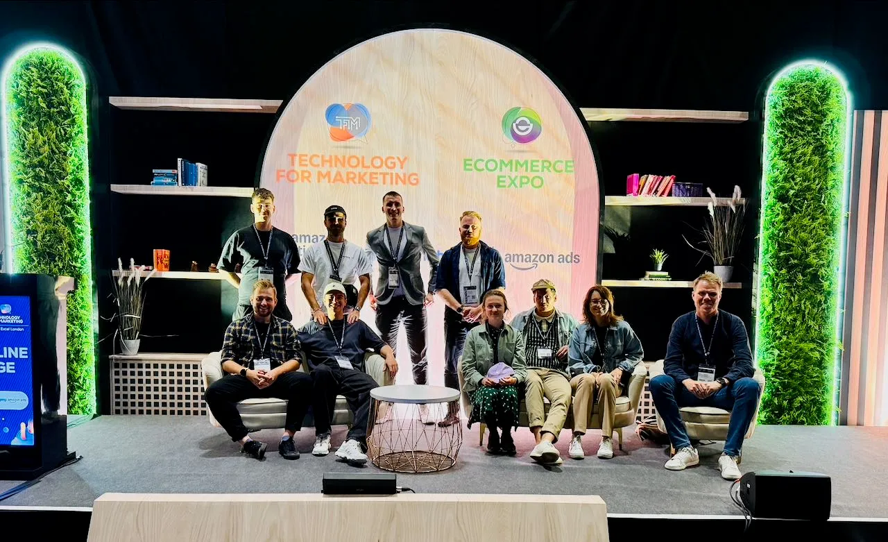 Skupina lidí na pódiu na výstavě Ecommerce Expo, obklopená dekoracemi a logy události.