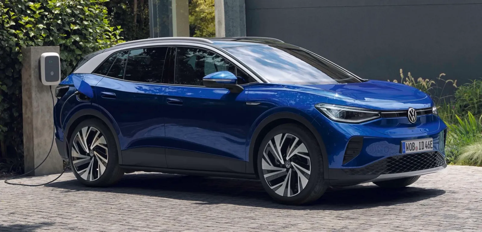 Elektroauto Volkswagen ID.4 nabíjené na stanici vedle moderní budovy.